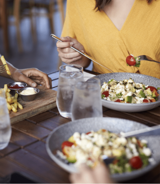 close up of female friends eating food at table in YMZBKX6